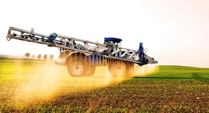 Machine agricole vaporisant un pesticide dans les champs