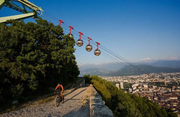 Grenoble: le téléphérique passant au dessus d'une route où passe un vélo