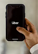 Une main qui tient un smartphone affichant le mot "Uber". Un bouleversement pourrait survenir chez Uber, suite à une décision de justice inattendue.