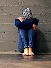 Une jeune femme assise, prostrée contre un mur pour illustrer la situation des étudiants précarisés