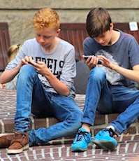 Deux adolescents assis avec leur smartphone pour une application StopCovid