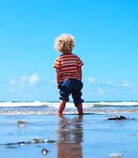 enfant sur la plage grâce à une aide aux vacances sociales 