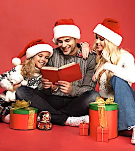 Deux parents avec leur fille, assis et portant des bonnets de Père Noël sur la tête Des fêtes de Noël restreintes, en petit comité, engendrent en France une ambiance morose.