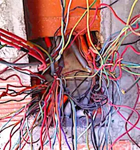 Un amas de fils électriques sortant d'un mur. Actuellement, le déploiement intensif de la fibre optique entraîne des ratés trop fréquents.