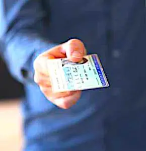 Une main d'homme qui tend une carte d'identité La carte nationale d’identité électronique représente une évolution importante, en terme de sécurité.