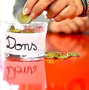Une main qui donne une pièce dans un verre destiné aux dons caritatifs. Grâce à une solidarité en hausse, à Lille, la Croix-Rouge a reçu plus de dons.