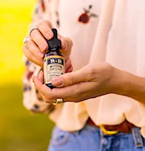 Deux mains qui tiennent un flacon de CBD une bouteille qui sert à usage du CBD en France