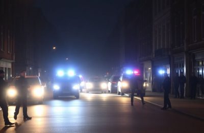 Scène nocturne en Belgique avec des policiers et des lumières.