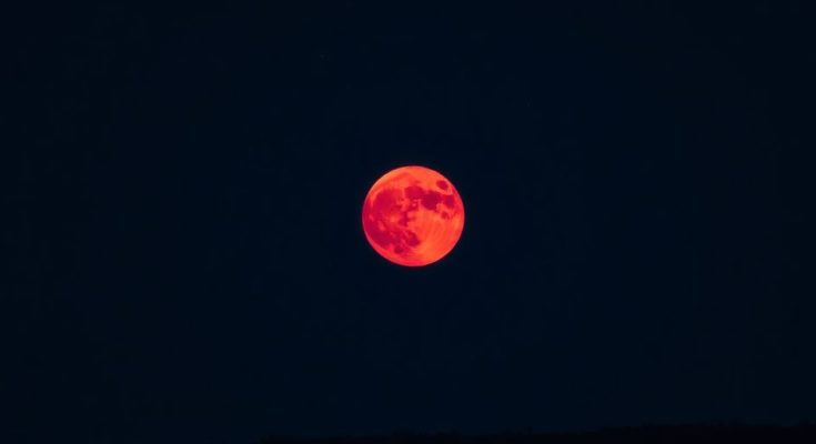 Éclipse de lune rouge dans un ciel étoilé.