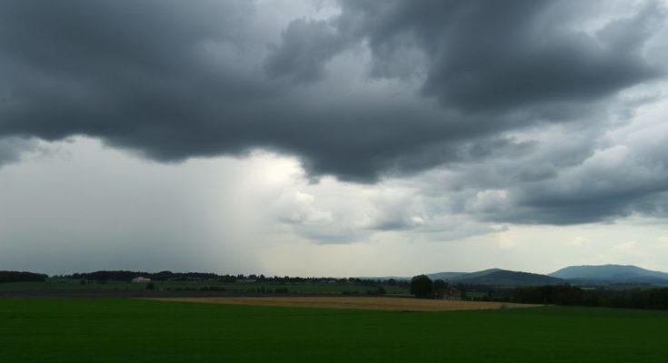 Ciel sombre et orageux au-dessus des champs verdoyants.
