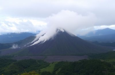 Volcan Poás en éruption, paysage verdoyant autour.