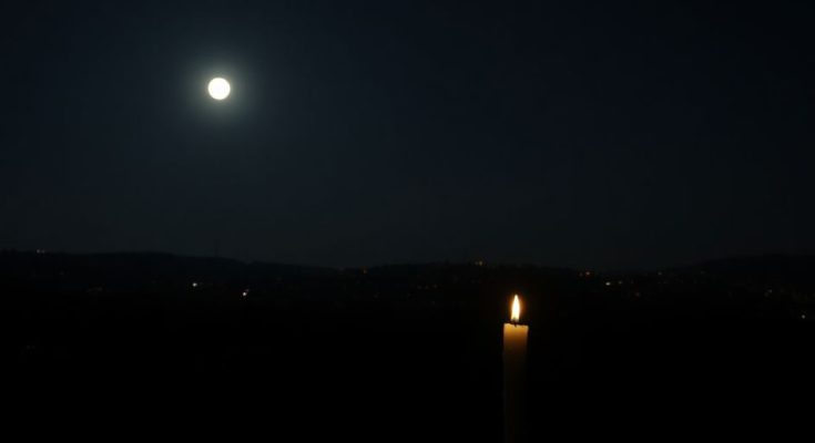 Ville sombre sans électricité, bougie éclairant la nuit.