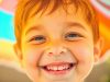 Enfant souriant sous un parasol coloré sur une plage ensoleillée