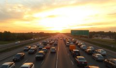 Autoroute embouteillée, voitures à l'arrêt, ciel nuageux au coucher du soleil.