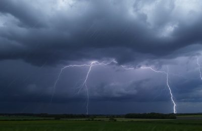 Ciel orageux menaçant avec éclairs sur des toits de maisons.