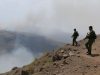 Soldats patrouillant une frontière, fumée visible.