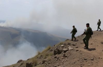 Soldats patrouillant une frontière, fumée visible.