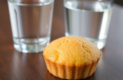 Une madeleine et un verre d'eau sur une table.