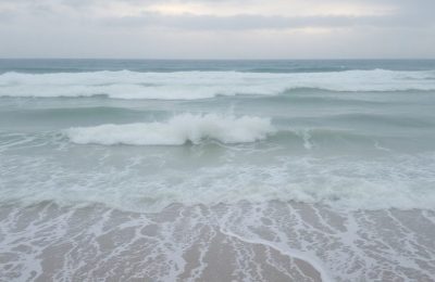 Vague puissante frappant une plage désertée par la houle.