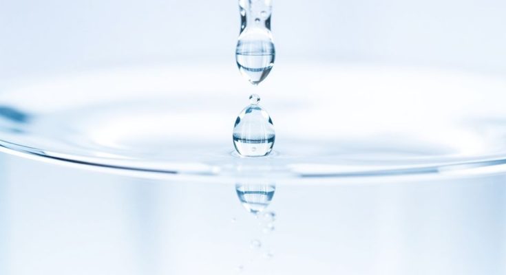 Gouttes d'eau cristallines tombant dans un récipient transparent.