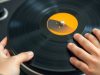 Un jeune homme tient un disque vinyle coloré.