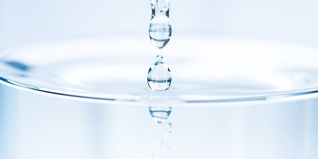 Gouttes d'eau cristallines tombant dans un récipient transparent.