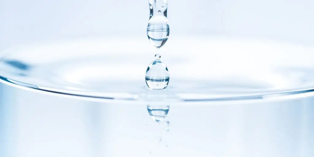 Gouttes d'eau cristallines tombant dans un récipient transparent.
