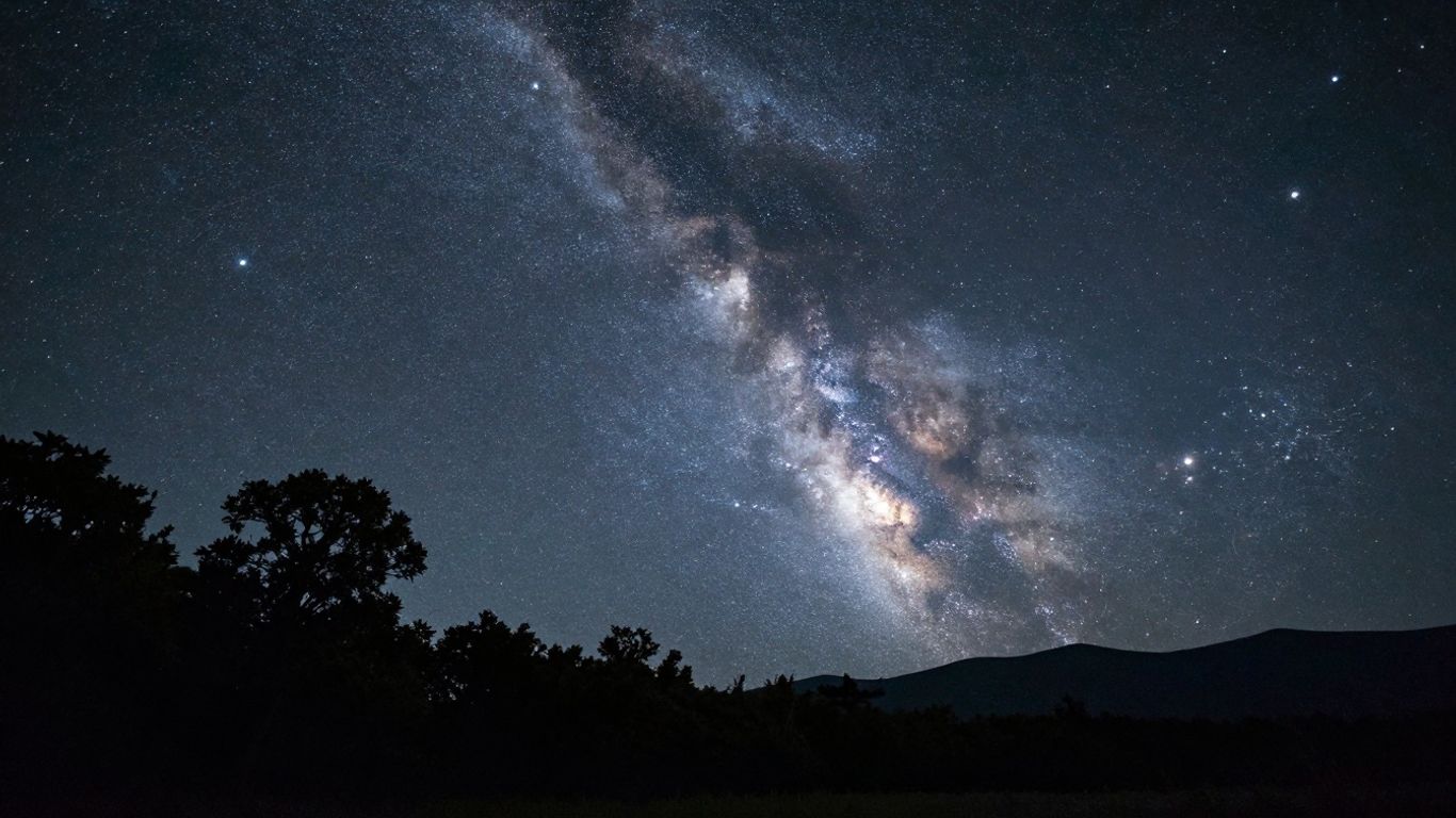 Ciel étoilé au-dessus d'un paysage naturel nocturne.