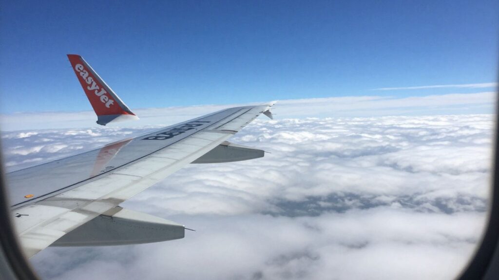 Avion EasyJet dans le ciel bleu avec des nuages blancs.