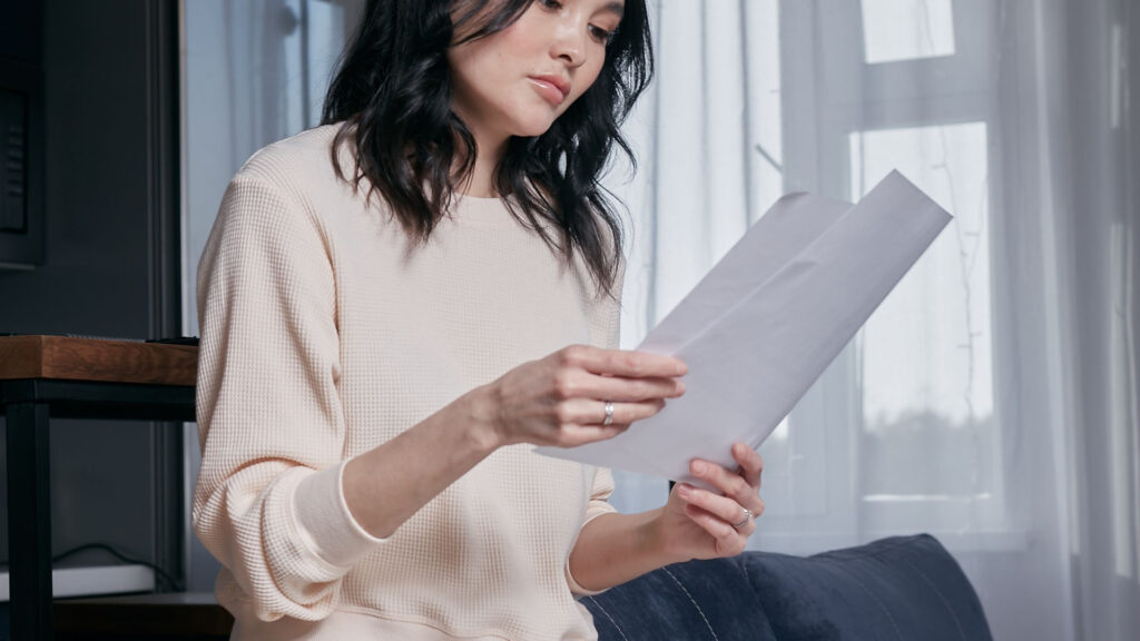 Femme de moins de 55 ans vérifiant des documents pour l’allocation veuvage