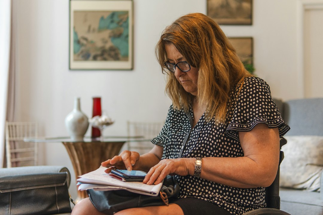 Une femme consulte son téléphone en remplissant des documents de pension