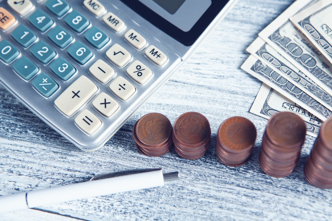 Une calculatrice, un stylo et de l’argent servent à préparer un versement d’épargne