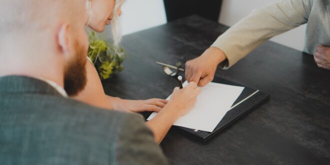 Couple signant des documents pour la vente d’un logement financé par un PTZ