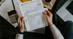 Une personne vérifie des documents fiscaux avec une calculatrice et un ordinateur