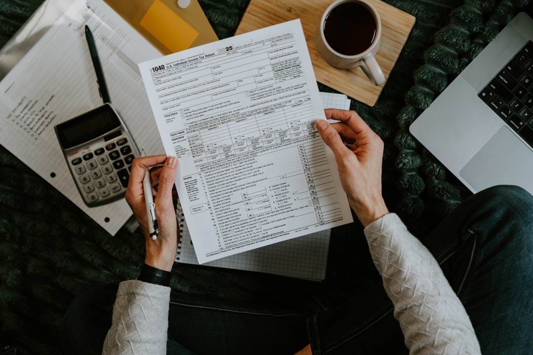 Une personne vérifie des documents fiscaux avec une calculatrice et un ordinateur