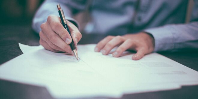 Une personne signe des documents liés à une succession
