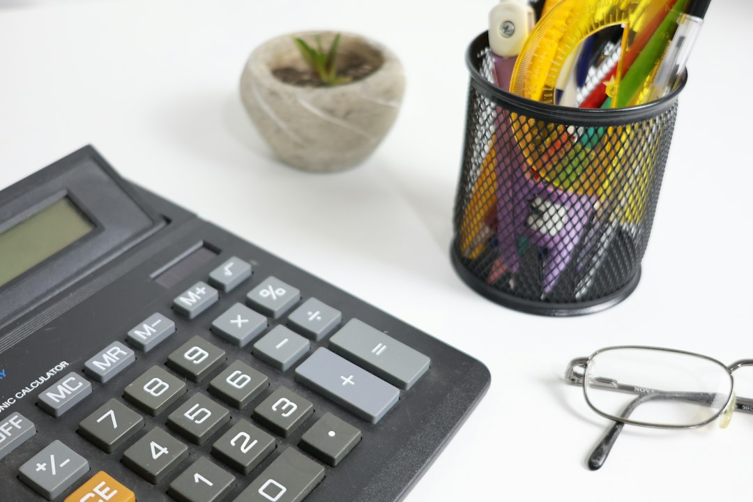 Calculatrice, lunettes et stylos sur un bureau blanc