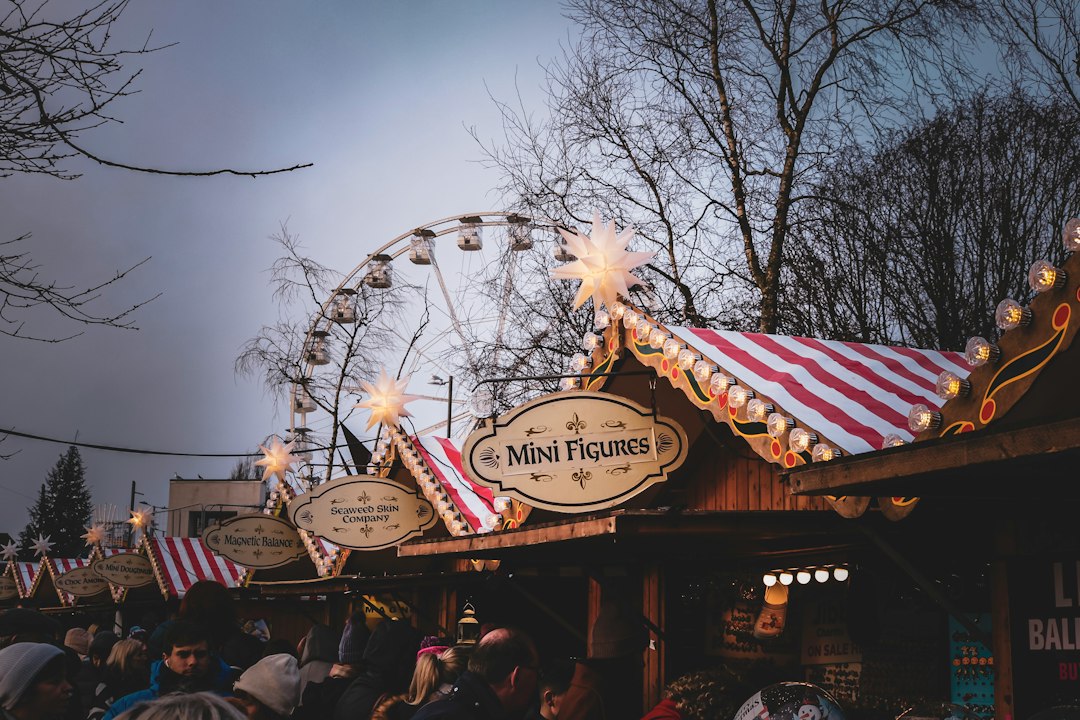 Grande roue illuminée derrière des stands de fête foraine