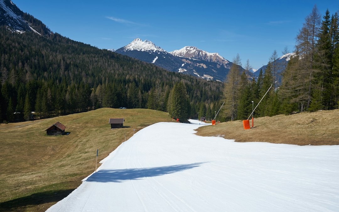 Piste de neige de culture entourée de prairies vertes, symbole du manque de neige en moyenne montagne